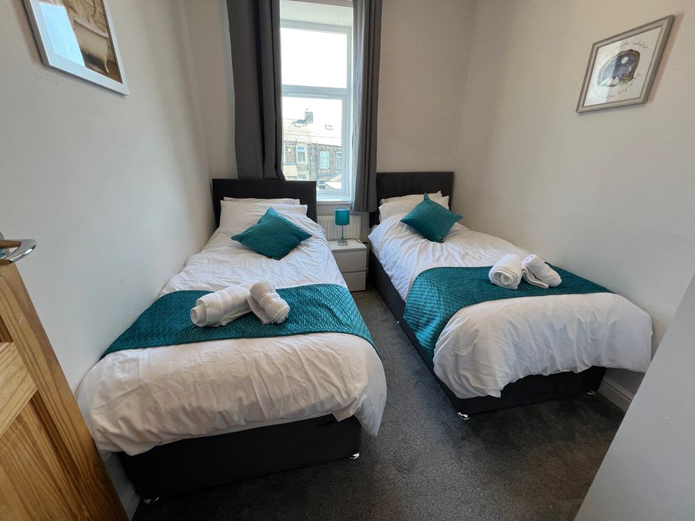 A bedroom with two single beds and a bedside table at Victoria Place in Accrington