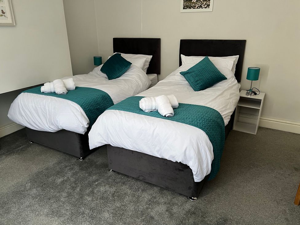 A bedroom with two single beds and a bedside table at Victoria Place in Accrington