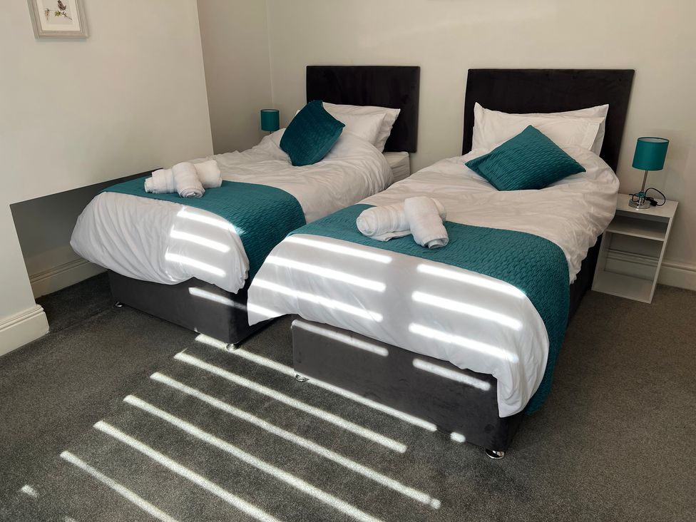 A bedroom with two single beds and bedside table at Victoria Place in Accrington