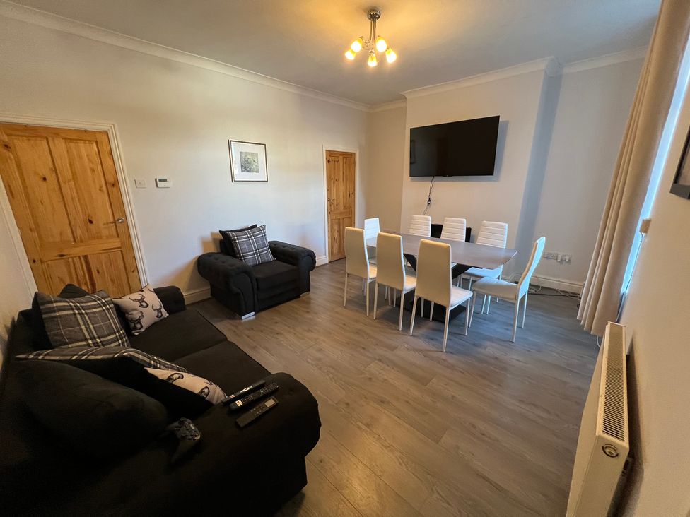 A living room with a sofa, table, chairs, and television at Victoria Place in Accrington