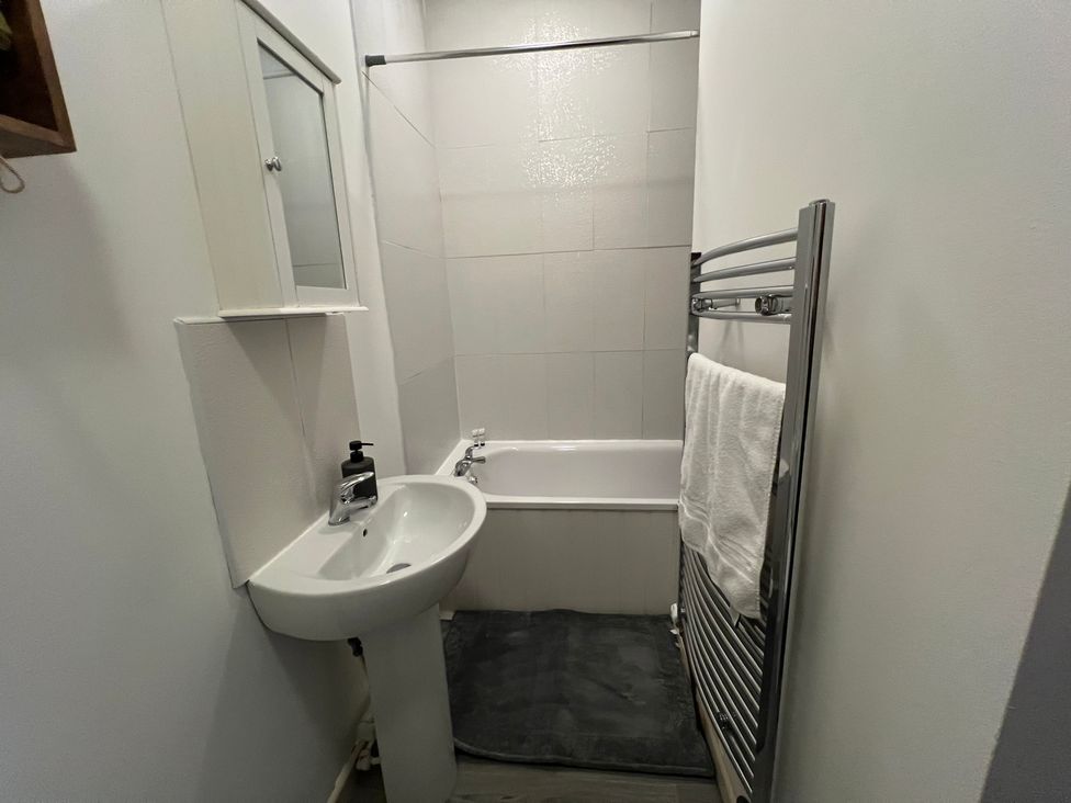 A bathroom with a bathtub, sink, and towel rail at Victoria Place in Accrington