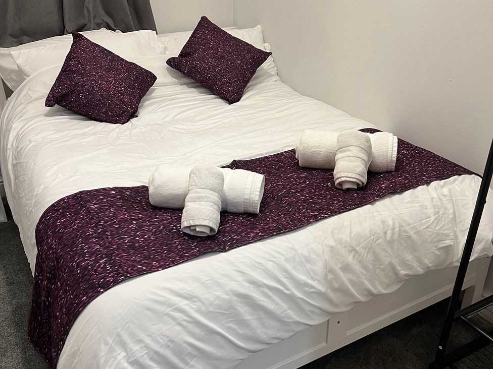 A bed with pillows and towels arranged at Victoria Place in Accrington
