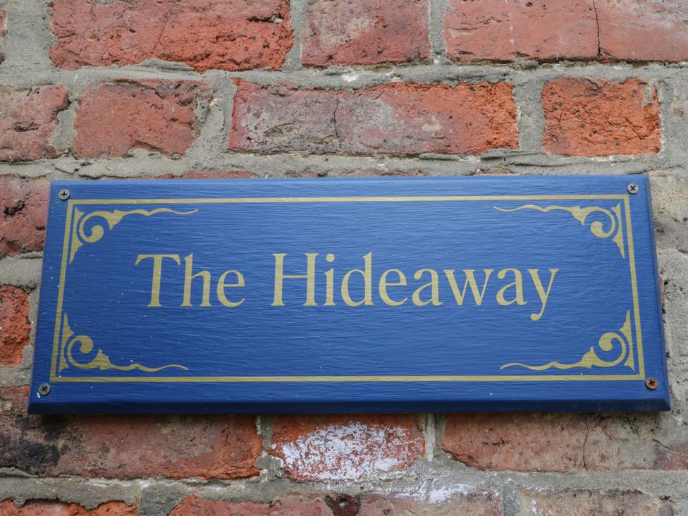 A sign that reads The Hideaway against a brick wall at The Hideaway in Whitby