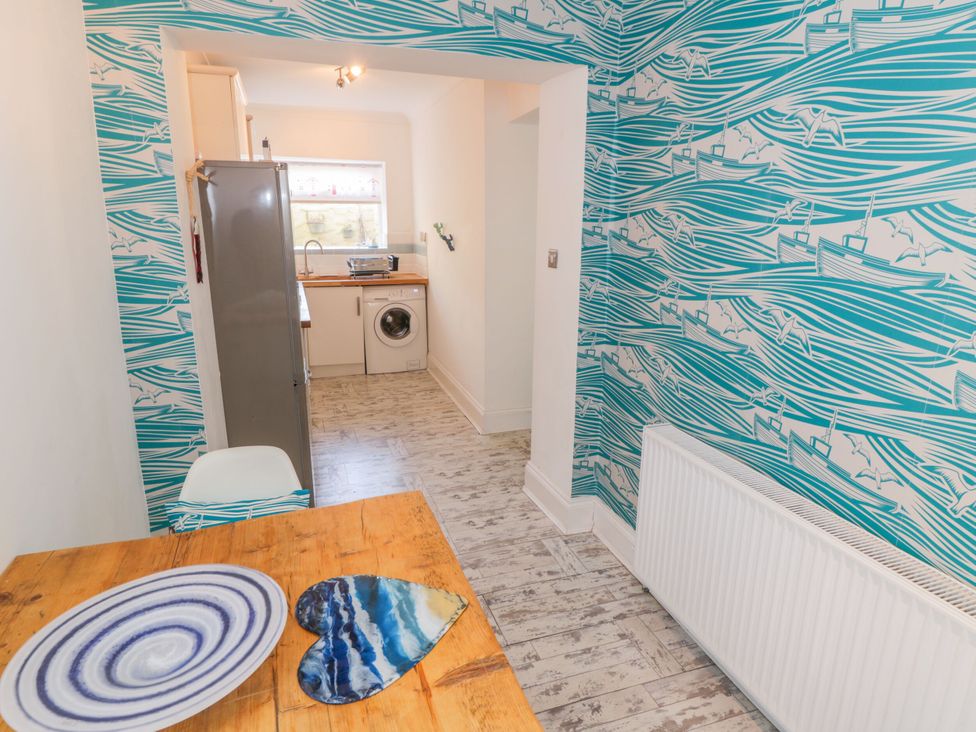 A kitchen with a table and refrigerator at The Hideaway in Whitby