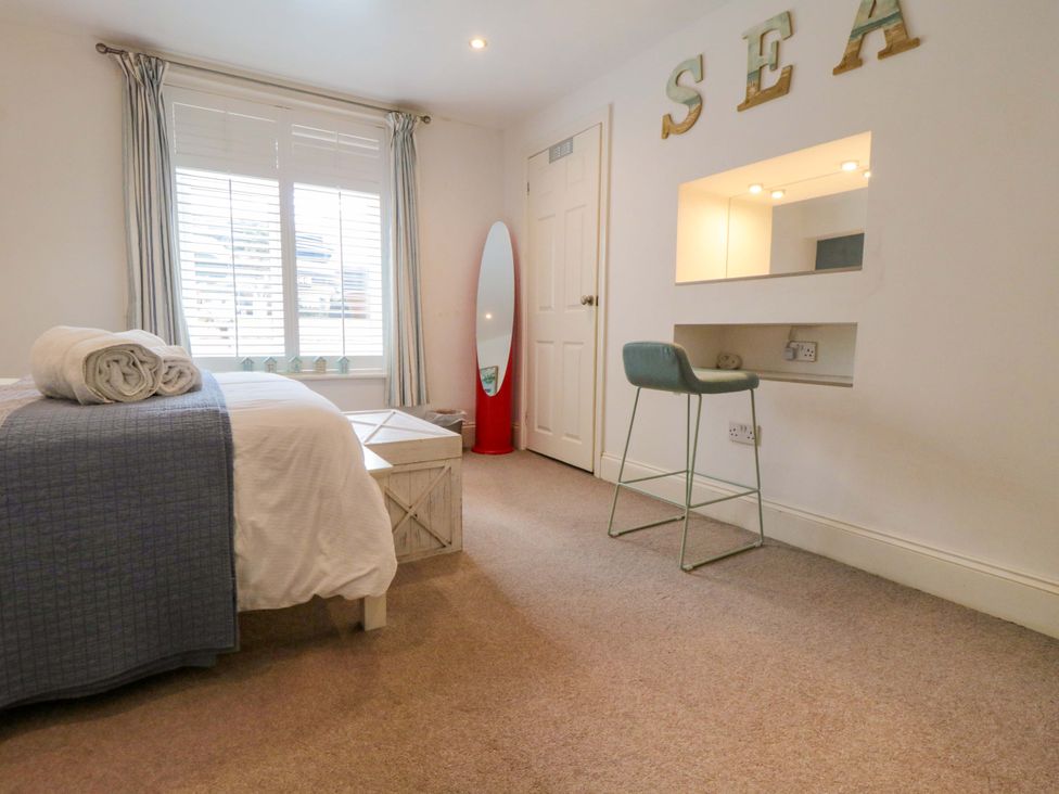 A bedroom with a bed, desk, and mirror at The Hideaway in Whitby