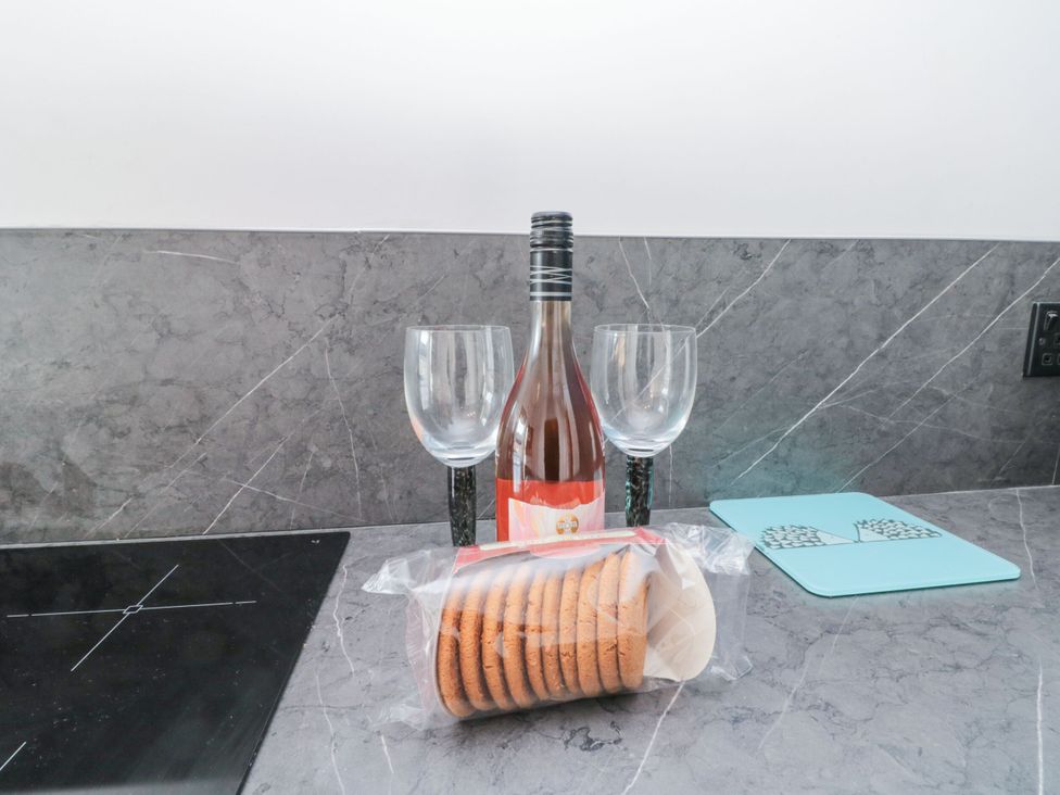 A kitchen counter with a wine bottle, two glasses, and a pack of cookies at Cuckoo's Nest in Whitby