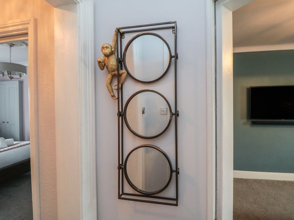 A decorative mirror with circular frames and a monkey figurine at Cuckoo's Nest in Whitby