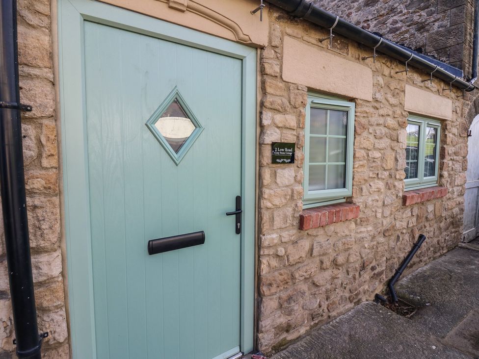A front entrance with a green door and stone wall at 2 Low Road