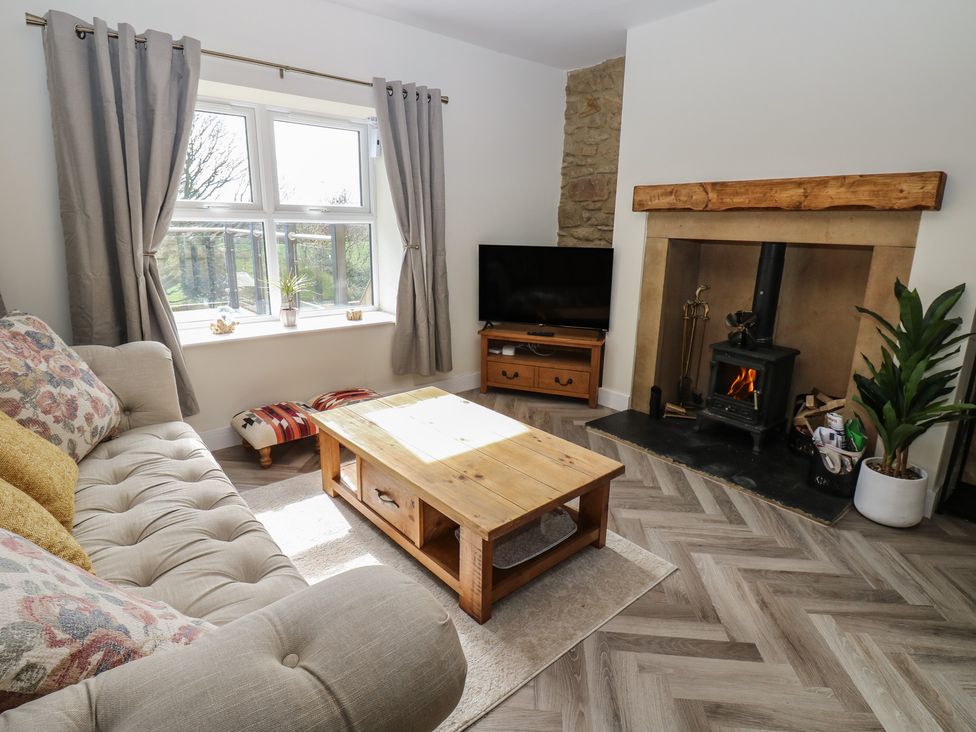 A living room with a sofa, television and fireplace at 2 Low Road