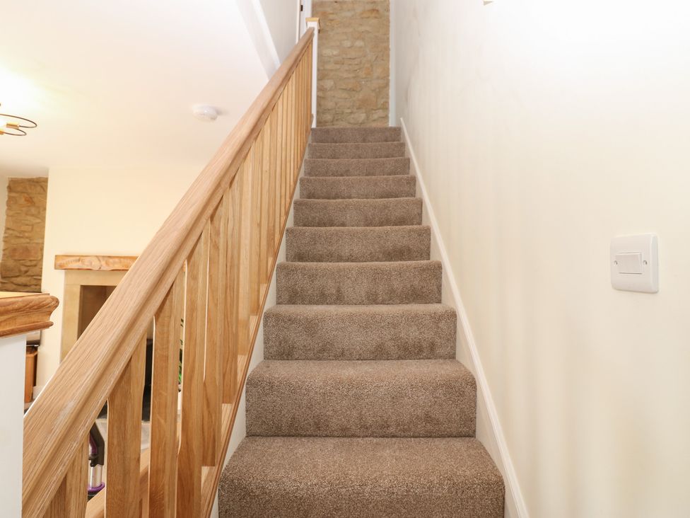 A staircase with a wooden handrail and carpet at 2 Low Road