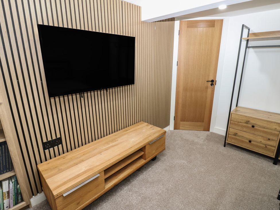 A living room with a television mounted on the wall at 2 Low Road