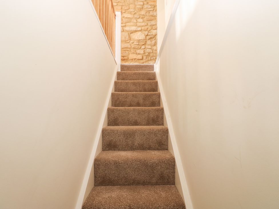 A staircase with carpet and stone wall at 2 Low Road 