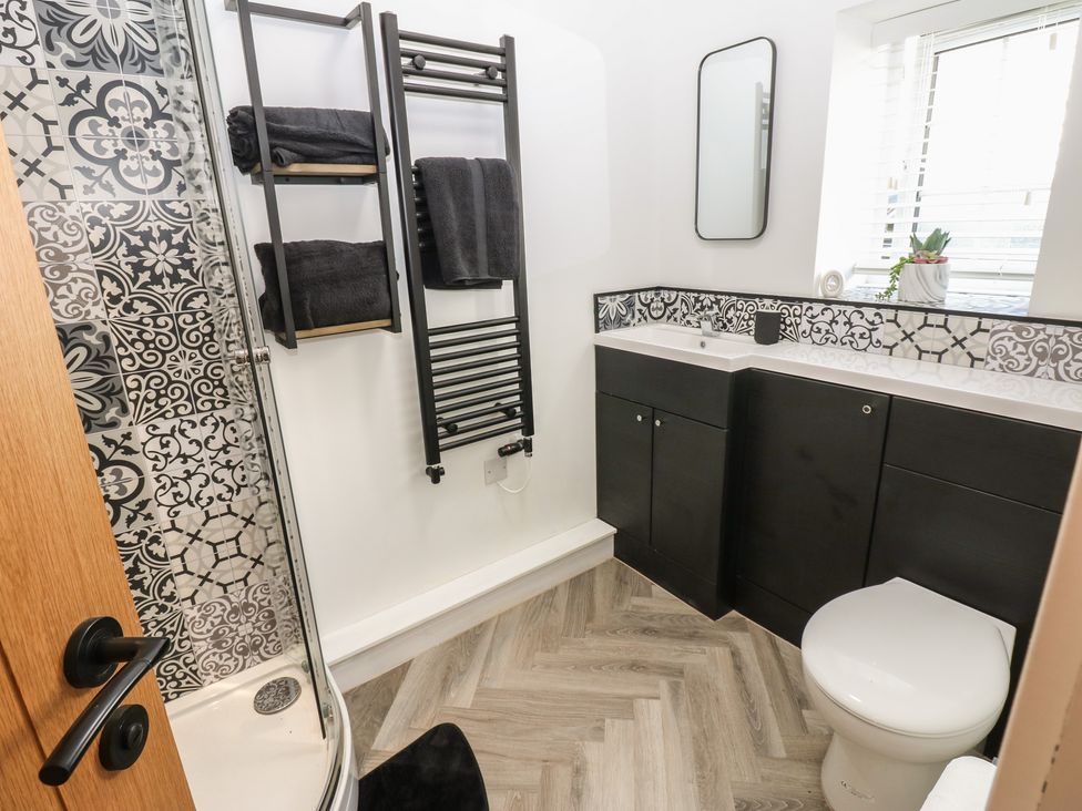 A bathroom with a shower, toilet, sink, and towel rack at 2 Low Road