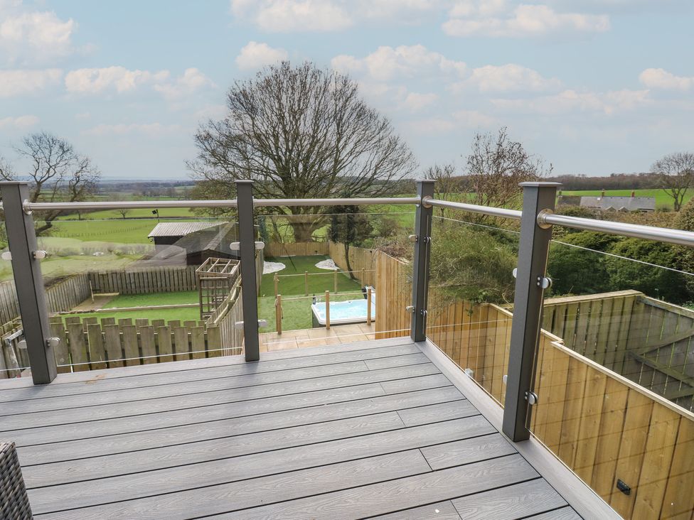 A deck with a view of a garden and hot tub at 2 Low Road