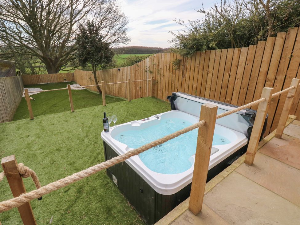 A hot tub in a garden with wine glasses at 2 Low Road