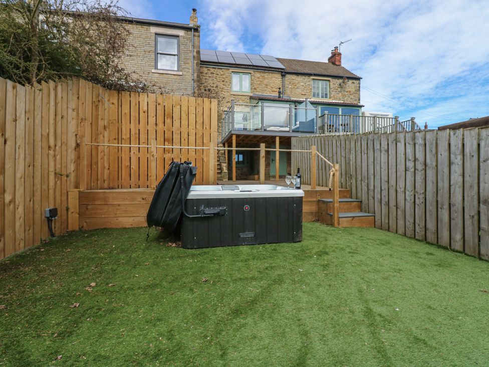 A garden with a hot tub and steps leading to a deck at 2 Low Road