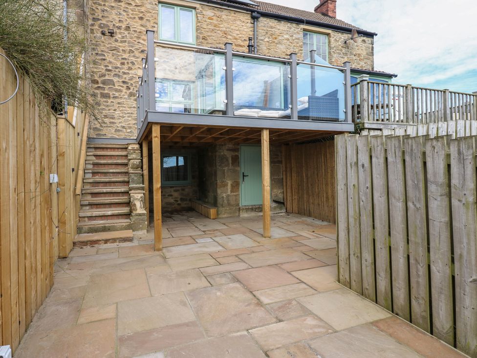 An outdoor area with a stone patio and a balcony at 2 Low Road 