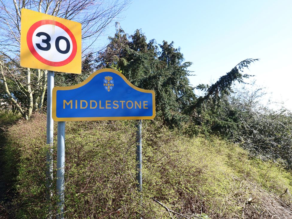 A 30 speed limit sign and Middlestone sign surrounded by trees and bushes