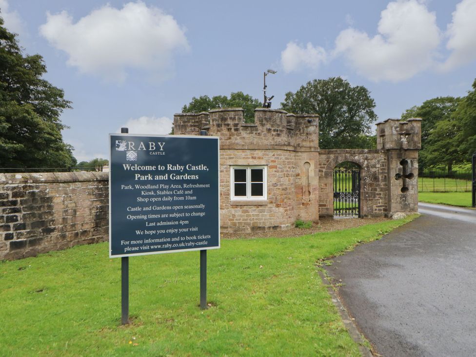 A sign for Raby Castle Park and Gardens with a stone gate at Raby Castle