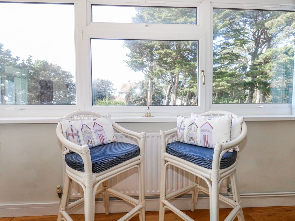 A sunroom with two chairs and cushions at Flat 17 Golden Gates in Poole
