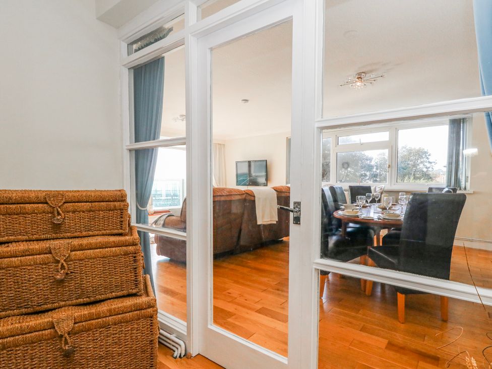 A dining room with a table and chairs visible through a glass door at Flat 17 Golden Gates in Poole