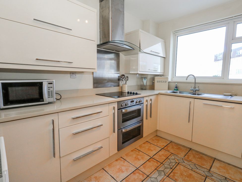 A kitchen with cabinets, stove, microwave, and sink at Flat 17 Golden Gates in Poole