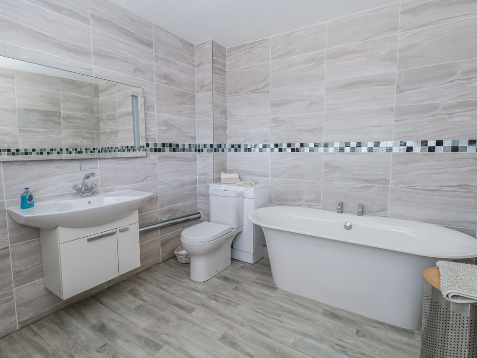 A bathroom with a bath tub, toilet, and sink at Flat 17 Golden Gates in Poole