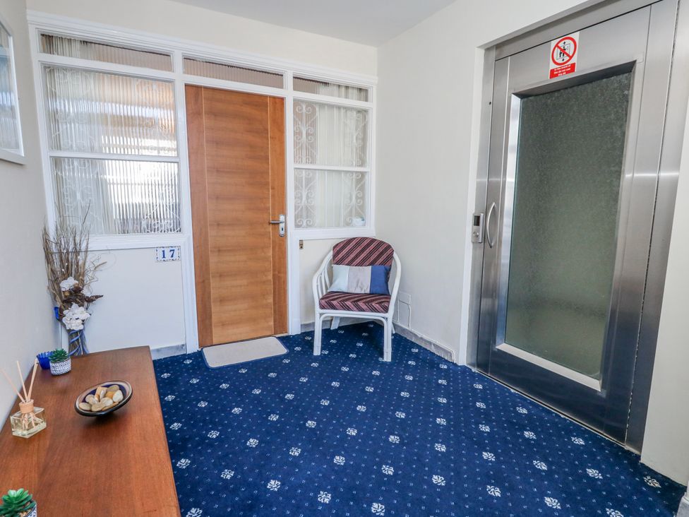 A hallway with a chair and elevator at Flat 17 Golden Gates Poole