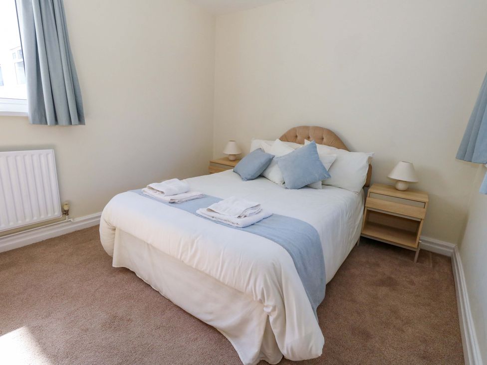 A bedroom with a bed and nightstands at Flat 17 Golden Gates Sandbanks