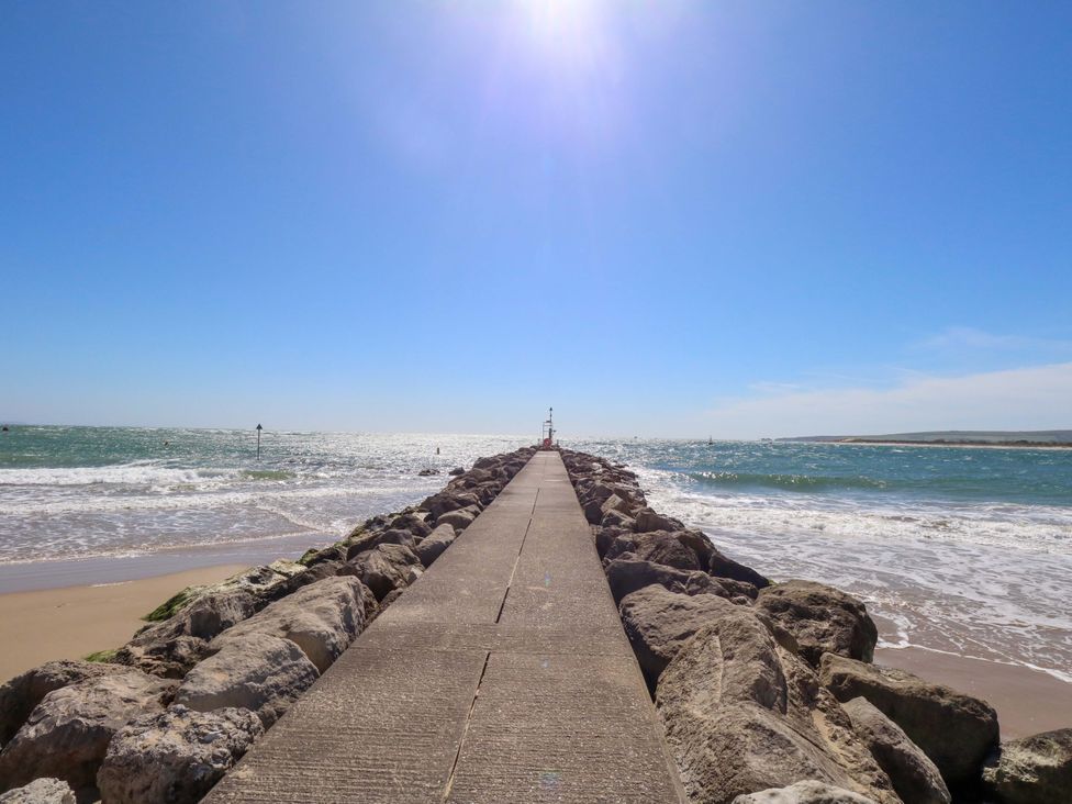 A pier with rocks leading to the water at Flat 17 Golden Gates in Sandbanks