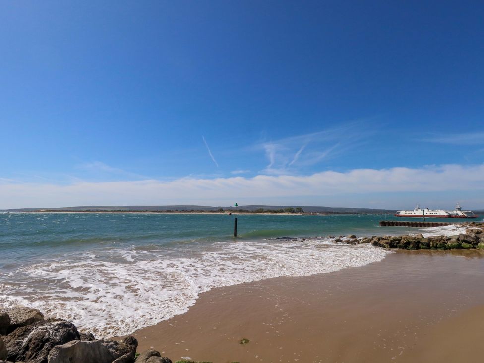 A beach view with water and a ferry at Flat 17 Golden Gates in Sandbanks