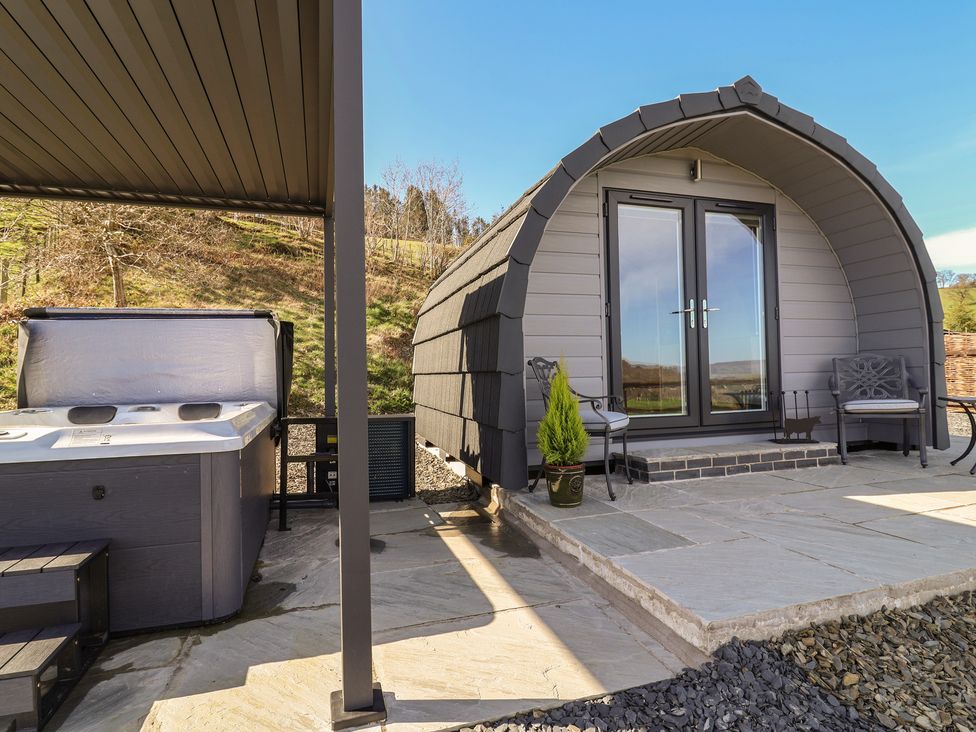 An outdoor area with a hot tub and seating at Cennin Pedr in Ruthin