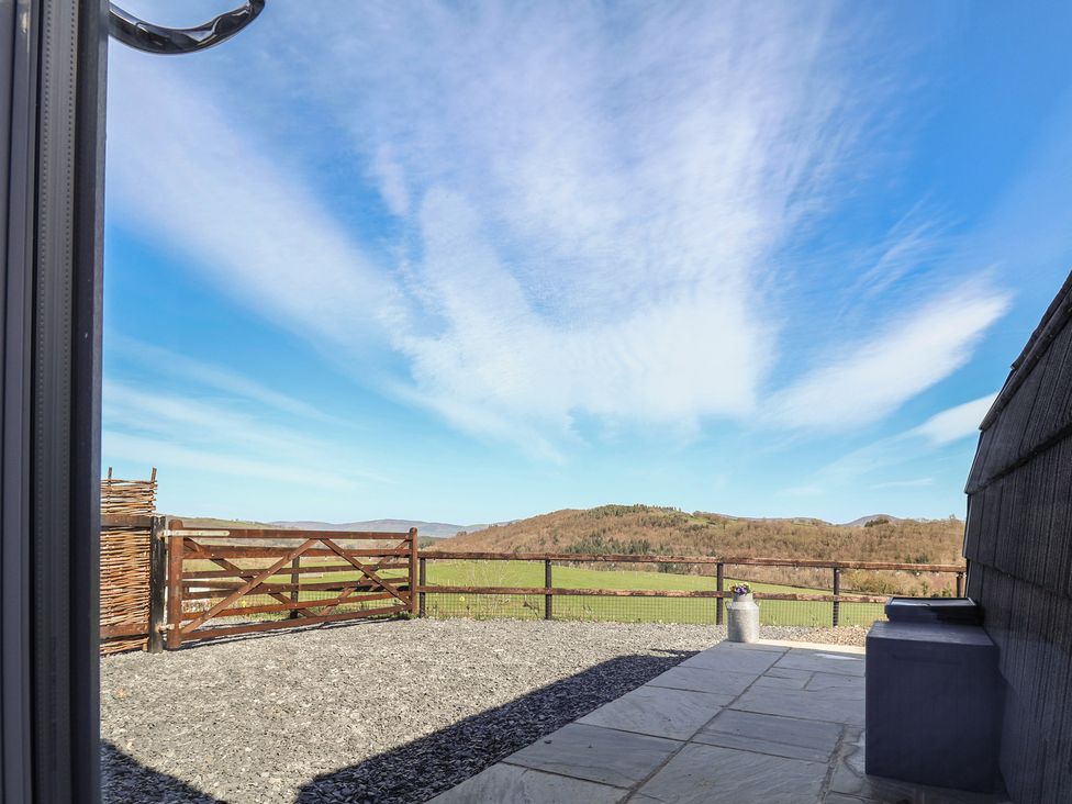 A garden view with a gate and gravel at Cennin Pedr in Ruthin