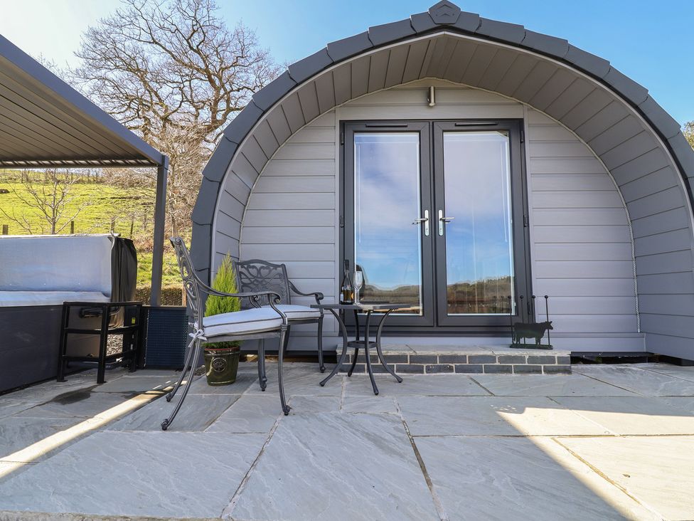 An outdoor seating area with a pod and furniture at Cennin Pedr in Ruthin