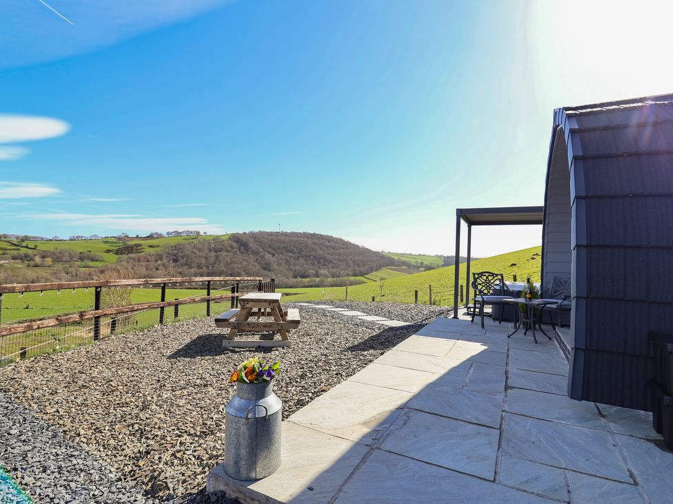 An outdoor area with a table and seating at Cennin Pedr in Ruthin