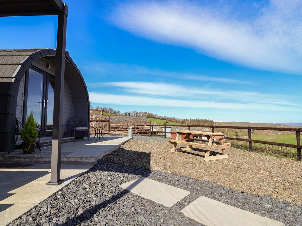 An outdoor area with a cabin, table, and benches at Cennin Pedr in Ruthin