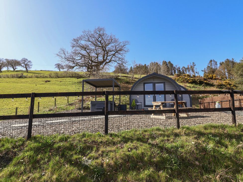 A cabin with a picnic table in front at Cennin Pedr in Ruthin