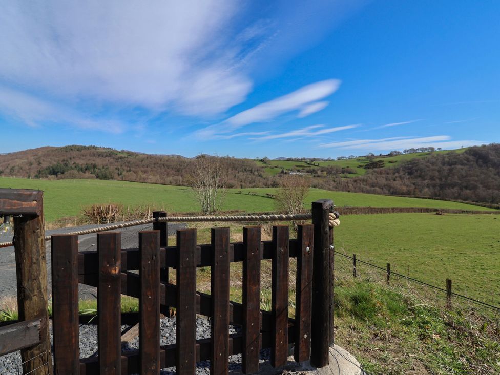 A gate overlooking a green field and hills at Cennin Pedr in Ruthin