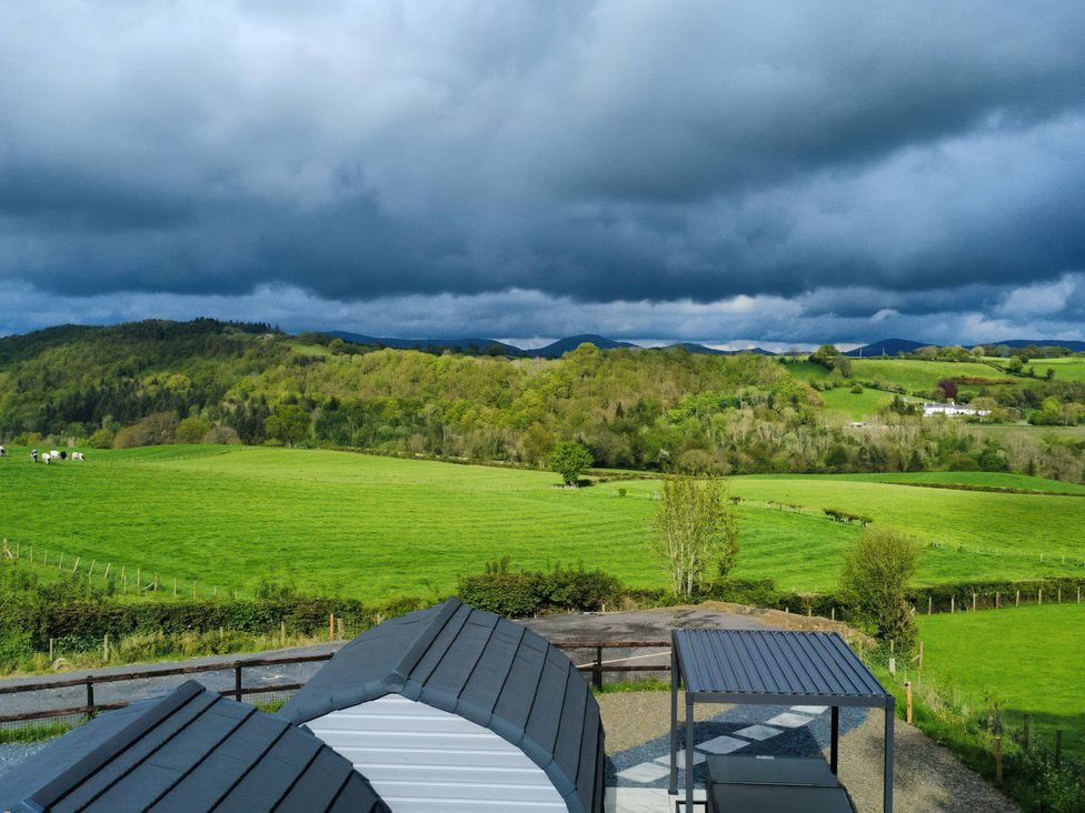 A view of green fields and hills with clouds at Cennin Pedr in Ruthin