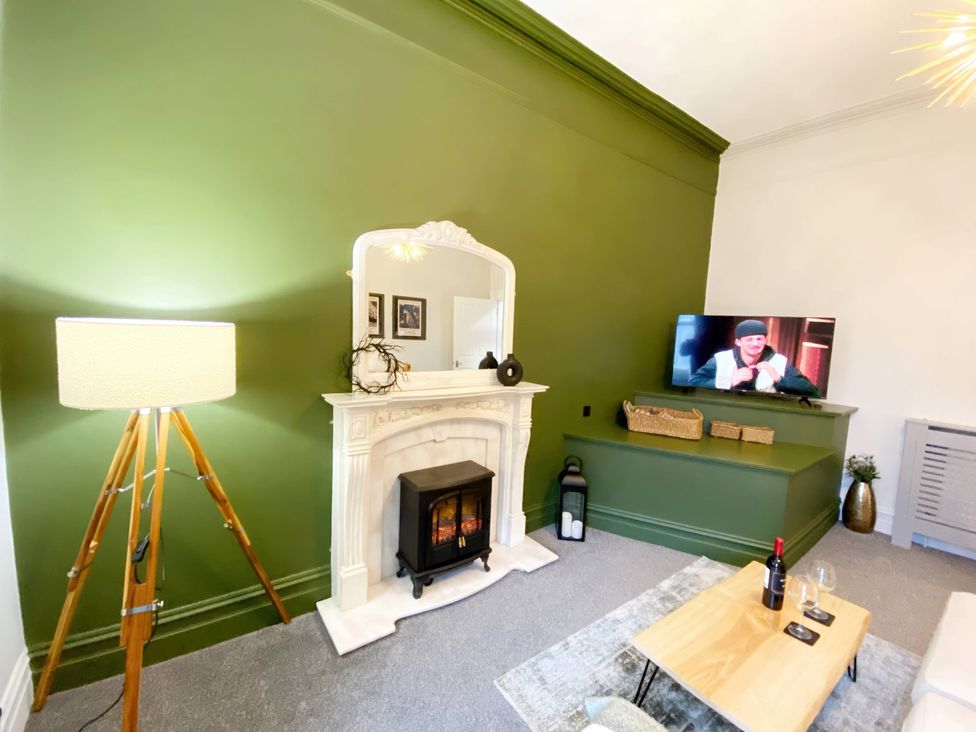 A living room with a fireplace and a television at 2B Redcliffe in Torquay