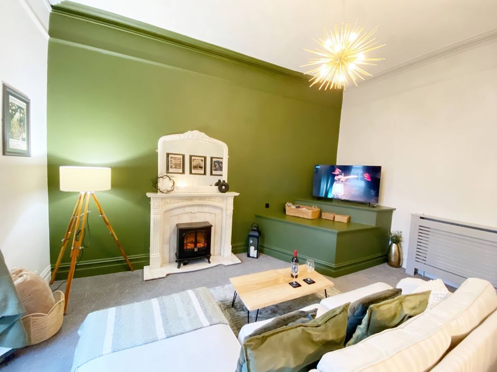 A living room with a sofa, coffee table, and television at 2B Redcliffe in Torquay