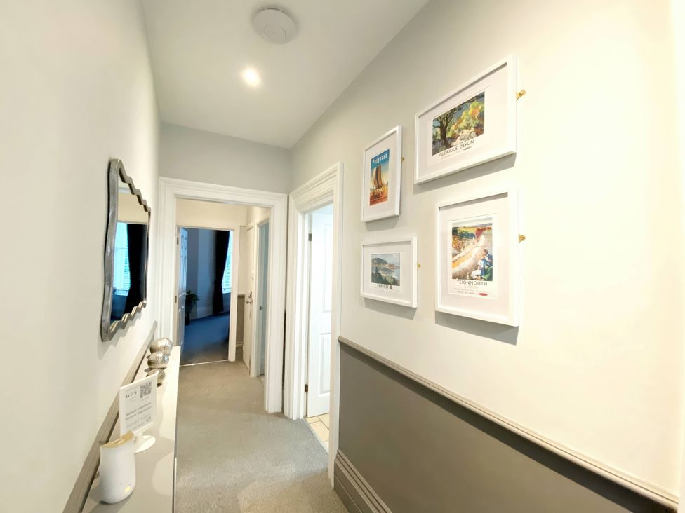 A hallway with a mirror and framed pictures at 2B Redcliffe in Torquay