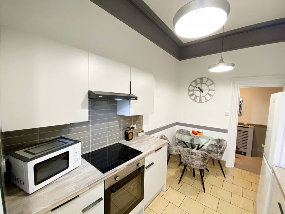 A kitchen with a microwave, oven, and dining table at 2B Redcliffe in Torquay