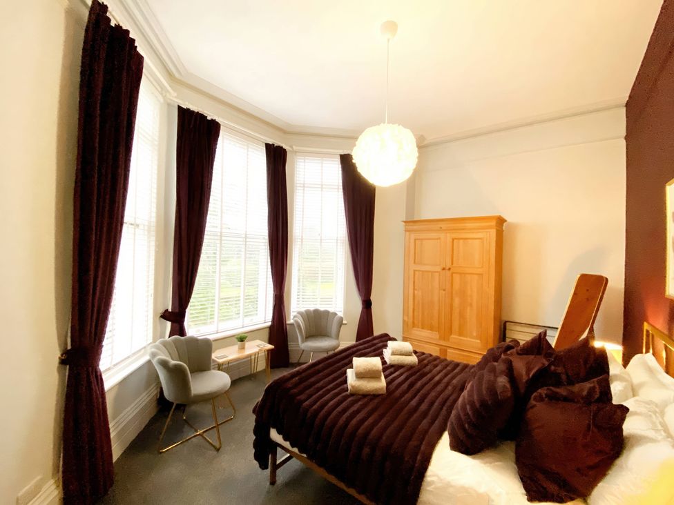 A bedroom with a bed and armchairs at 2B Redcliffe in Torquay