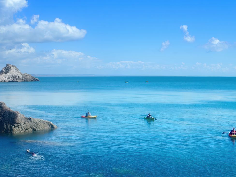 A view of kayakers on the ocean near rocks in the distance