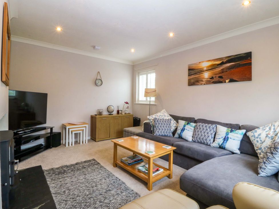 A living room with a sofa and television at 5 Ger Afon in Llanbedrog