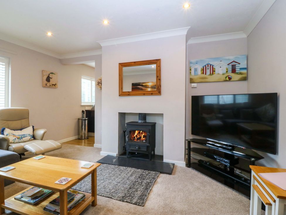 A living room with a fireplace and television at 5 Ger Afon in Llanbedrog