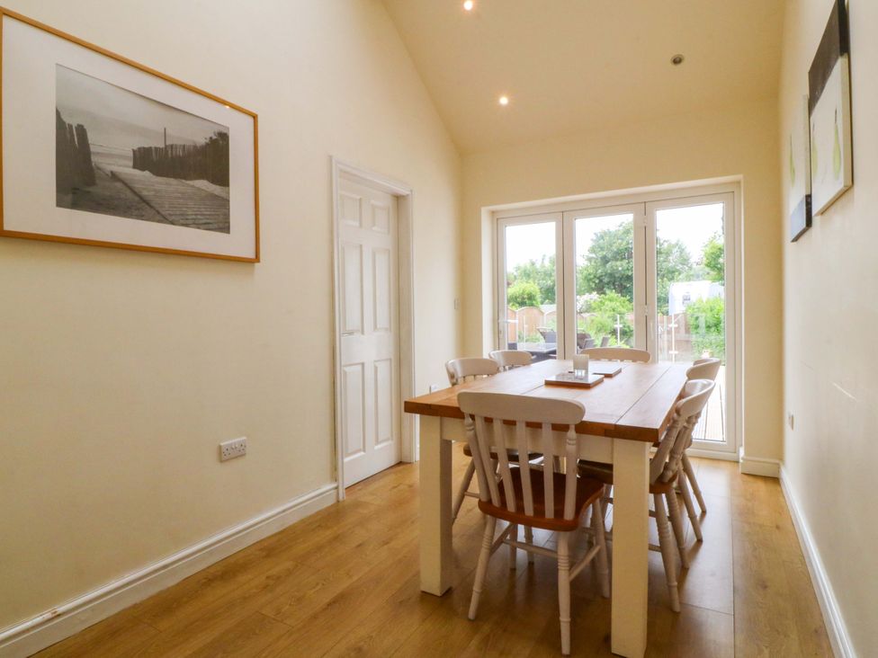 A dining room with a table and chairs at 5 Ger Afon in Llanbedrog