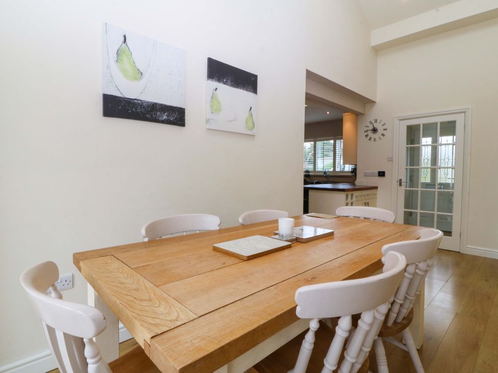 A dining room with a wooden table and chairs at 5 Ger Afon in Llanbedrog
