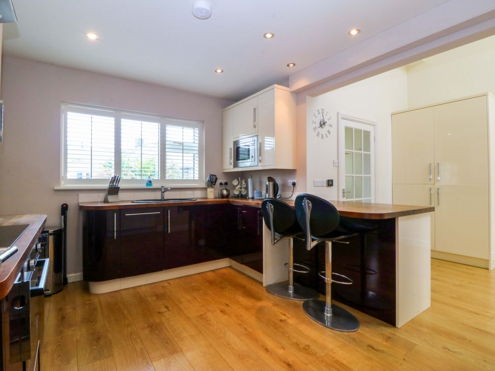 A kitchen with a countertop and bar stools at 5 Ger Afon in Llanbedrog